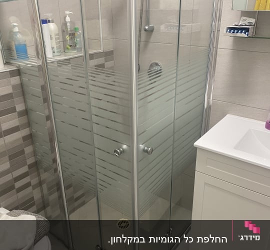 מקלחון זכוכית עם מוצרי טיפוח בחדר אמבטיה